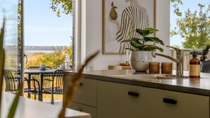 Een moderne keuken met een groot raam, een potplant en een schilderij aan de muur.