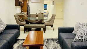 A modern living room with a sofa set, a coffee table, and a dining area with chairs and a table. - Luxury apartment with ocean view in the golden zone (Mazatlán)