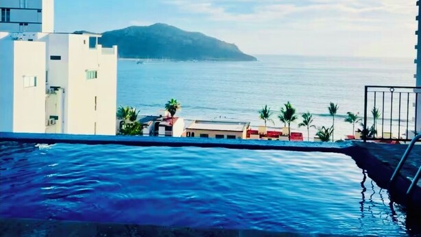 A swimming pool with a view of the sea and a distant island. - Luxury apartment with ocean view in the golden zone (Mazatlán)