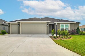 A single-story house with a garage, a front lawn, and a clear sky.