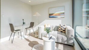 Una sala de estar moderna con un sofá, sillas, una mesita y una lámpara de pie.