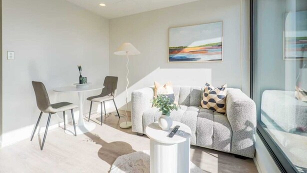 Un salon moderne avec un canapé, des fauteuils, une petite table et une lampe sur pied.