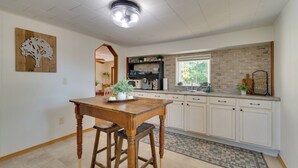 Eine Küche mit Holztisch, weißen Schränken, einer Ziegelrückwand und einer Deckenleuchte.