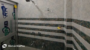 Casa de banho com chuveiro, suporte para toalhas e parede revestida com padrão decorativo.