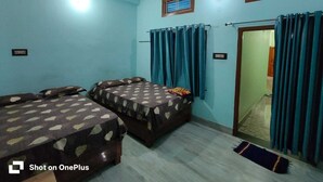 Quarto com duas camas, ventilador no teto e janela com cortinas.