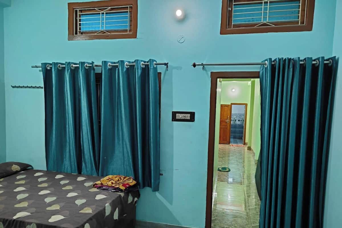 Un dormitorio con cama, cortinas y una puerta que da a otra habitación.