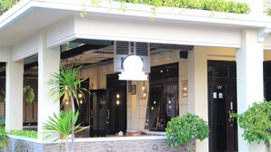 A building with a covered entrance, potted plants, and a hanging light fixture. - Hotel Setia Budi Madiun (Madiun)