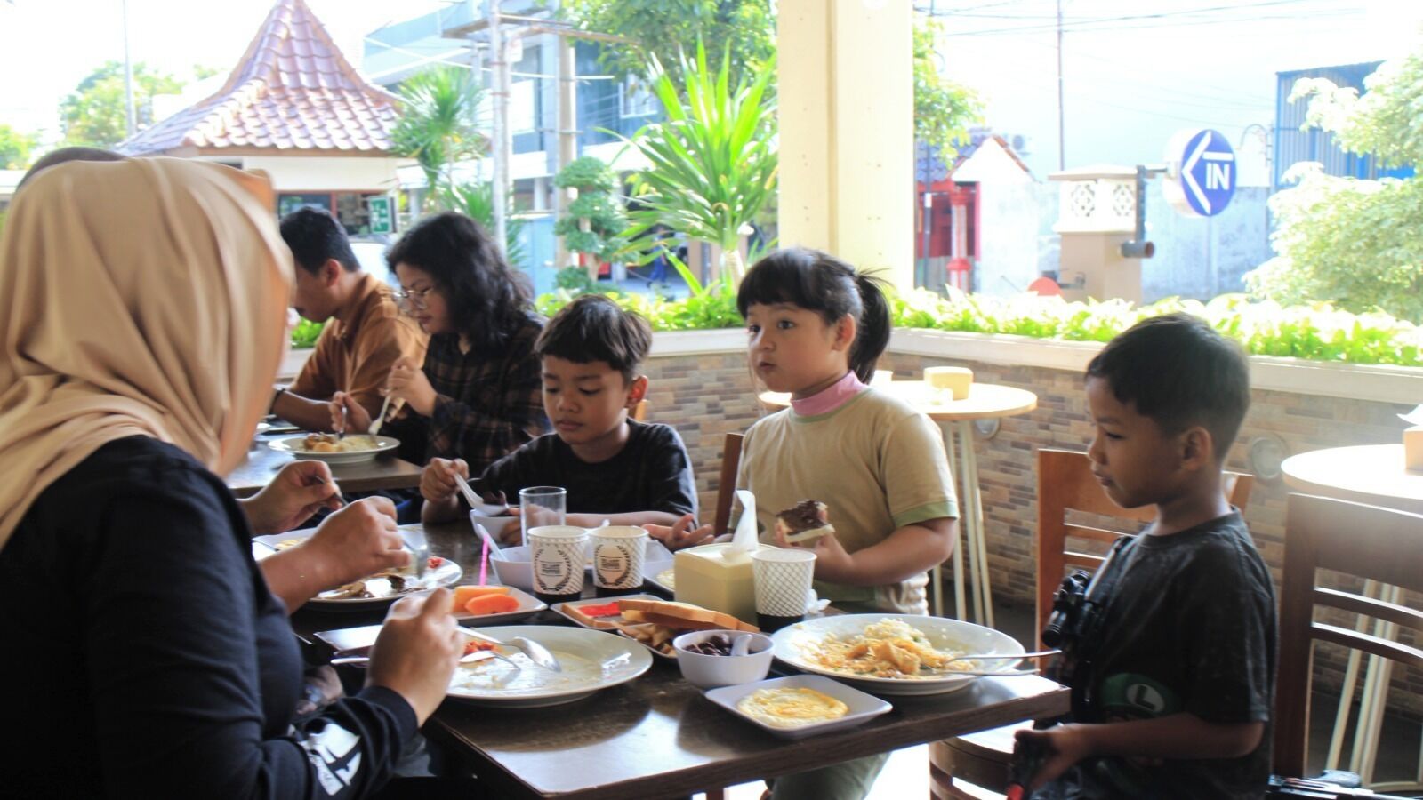 A group of people dining at an outdoor table with various dishes and drinks.