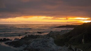A coastal landscape with rocky terrain and a view of the ocean during sunset. - Hermanus Family Getaway - Near The Beach (Hermanus)
