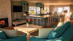 A spacious living room with a fireplace, a bar area, and a dining space. - Hermanus Family Getaway - Near The Beach (Hermanus)
