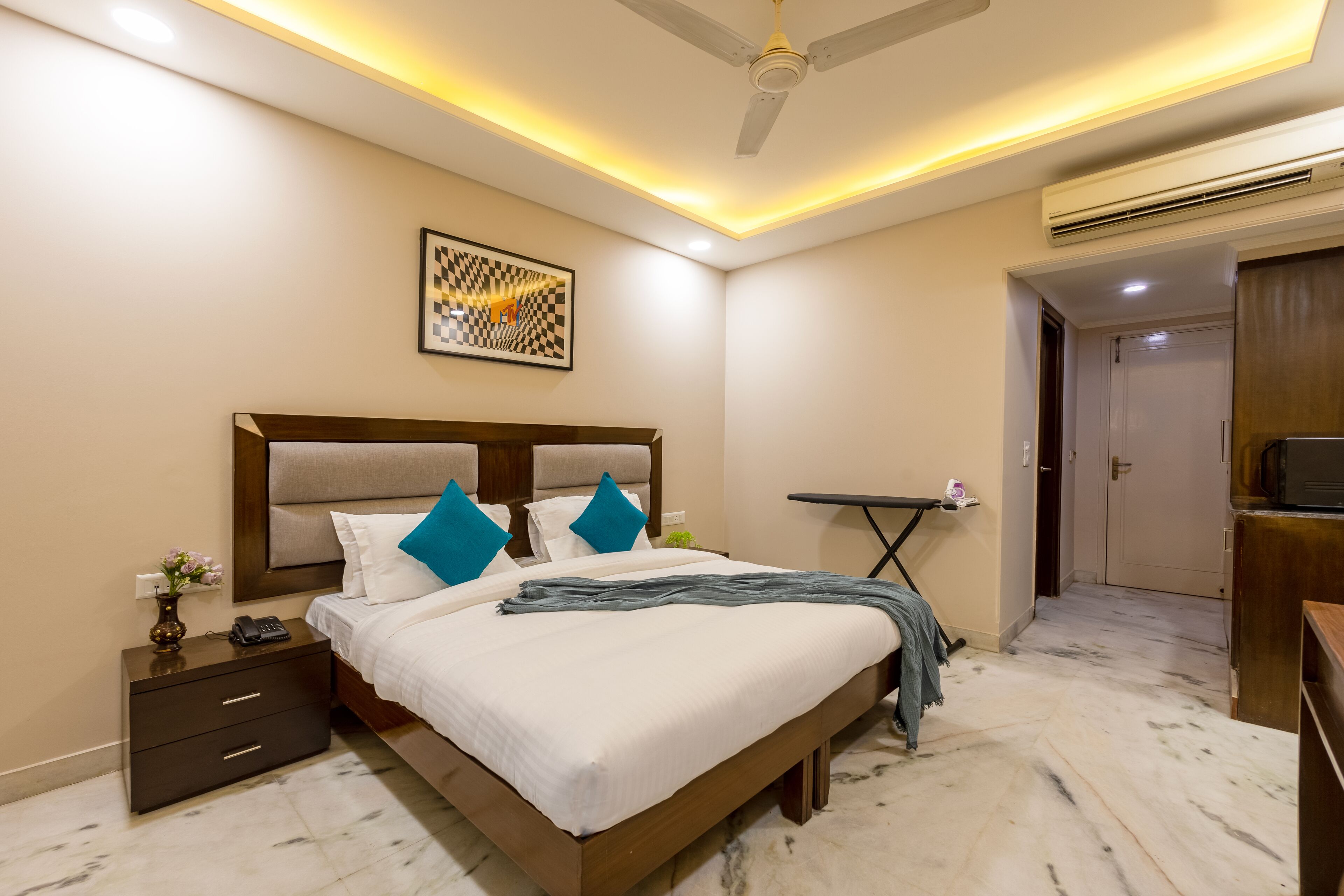 Habitación de hotel con cama, mesita de noche y ventilador de techo.