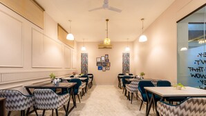 A dining area with marble flooring, multiple tables and chairs, pendant lighting, and framed artwork on the walls.