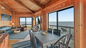 Een houten chalet met een eethoek, een bank en uitzicht op het water.