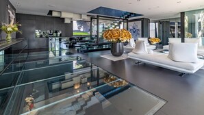 Een moderne keuken met glazen aanrechtbladen, een centraal eiland en een zithoek met witte banken.