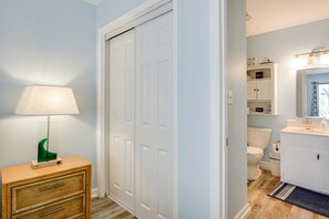A bathroom with a toilet, a sink, a mirror, a cabinet, and a wooden dresser with drawers. - Direct Beach Access! Walkable Condo on Ocean Blvd (North Myrtle Beach)