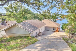 A residential area with houses, a driveway, and a body of water in the background. - Boat, Fish & Explore! Gem on Lake of the Ozarks (Roach)