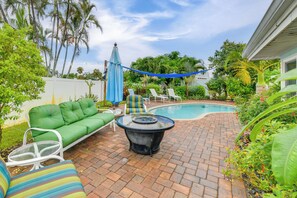 A backyard with a swimming pool, a green sofa, white chairs, and a table. - Private Hot Tub, Pool & Yard: Modern Bradenton Gem (Bradenton)
