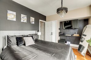 Une chambre à coucher moderne avec un grand lit, un lustre et des œuvres d’art accrochées au mur.