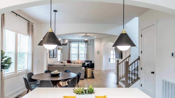 Una cocina moderna con una isla central, iluminación colgante y un comedor con una mesa redonda y sillas.