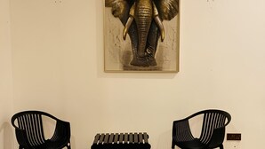 A room with a framed elephant artwork on the wall, two black chairs, and a bench. - Hmc Leisure Villa Dewundara (matara)