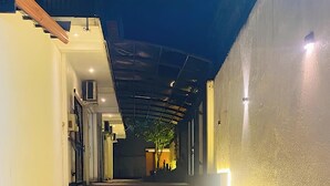 A narrow alleyway with a tiled floor, a covered area with a roof, and a wall with a light strip. - Hmc Leisure Villa Dewundara (matara)