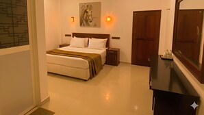 A hotel room with a bed, bedside tables, a ceiling fan, a painting, wall sconces, a mirror, and a wardrobe. - Hmc Leisure Villa Dewundara (matara)