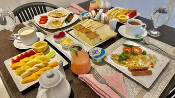 A breakfast table with various dishes including eggs, toast, fruit, and beverages.