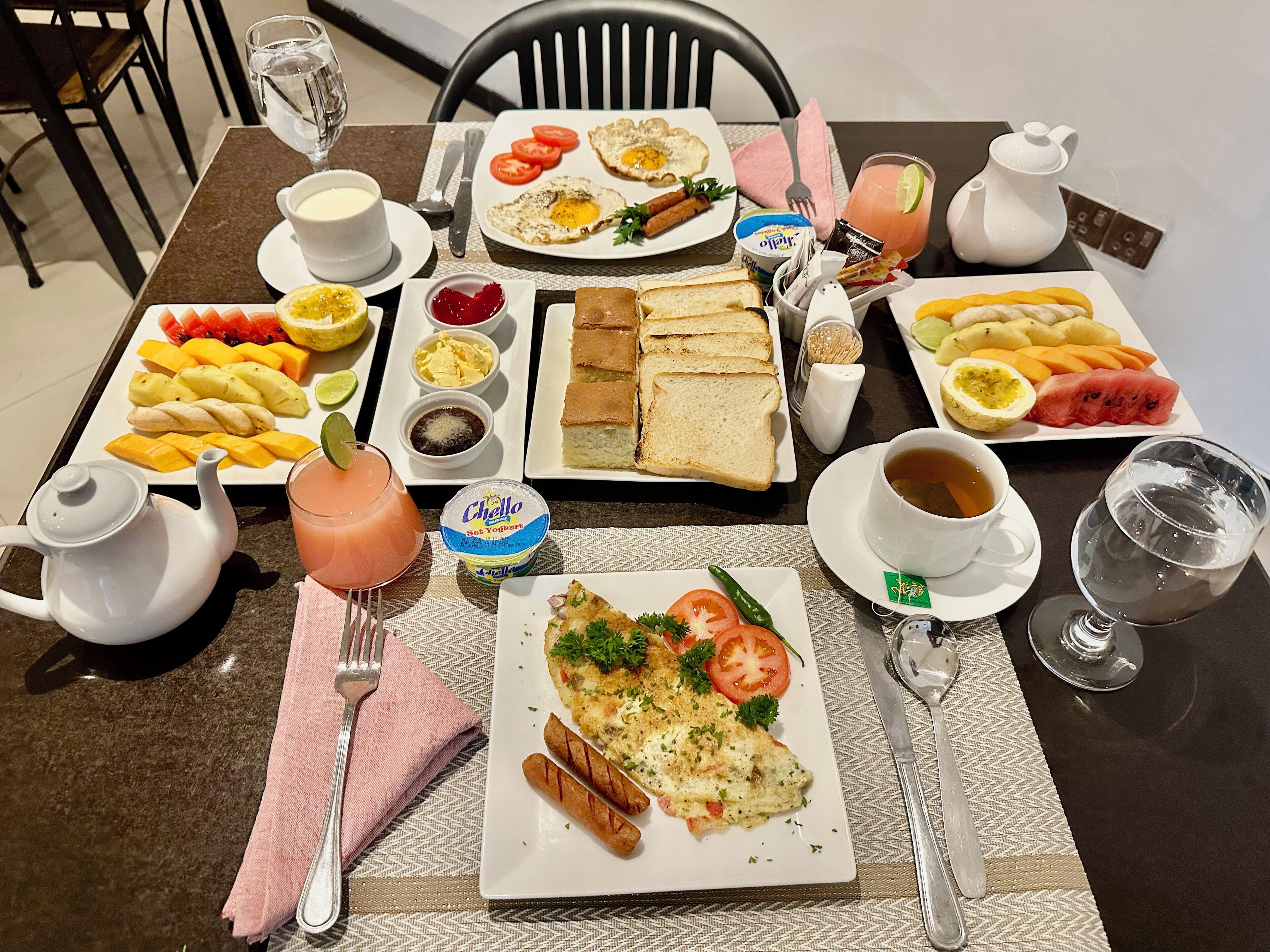 A breakfast table with various dishes, including eggs, toast, fruit, and beverages.