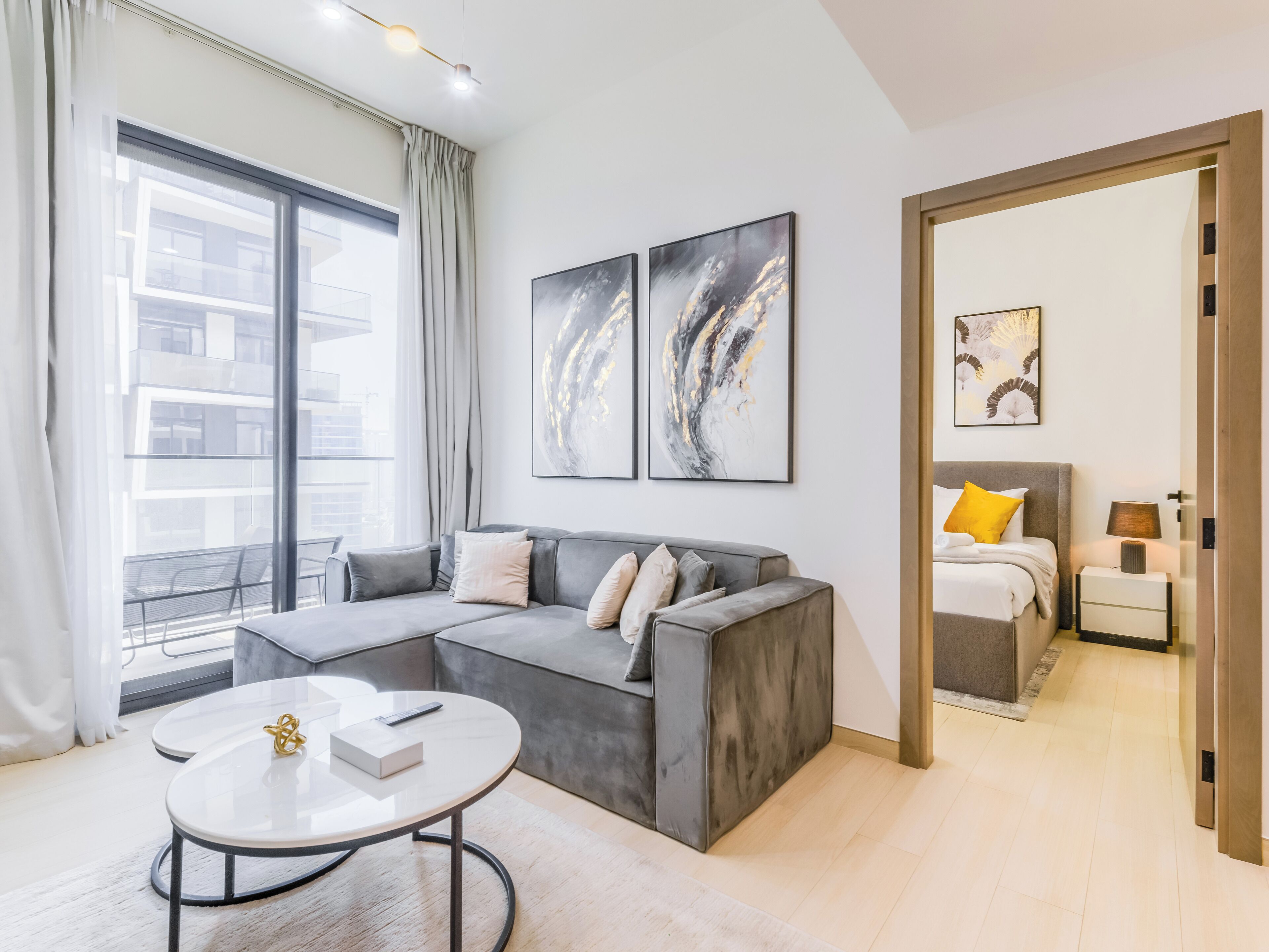 A modern living room with a grey sectional sofa, a round coffee table, and artwork on the walls.