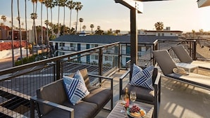 A rooftop terrace with a pool, lounge chairs, and a table with snacks and drinks.