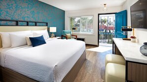 A hotel room with a large bed, a desk, and a balcony with a view.