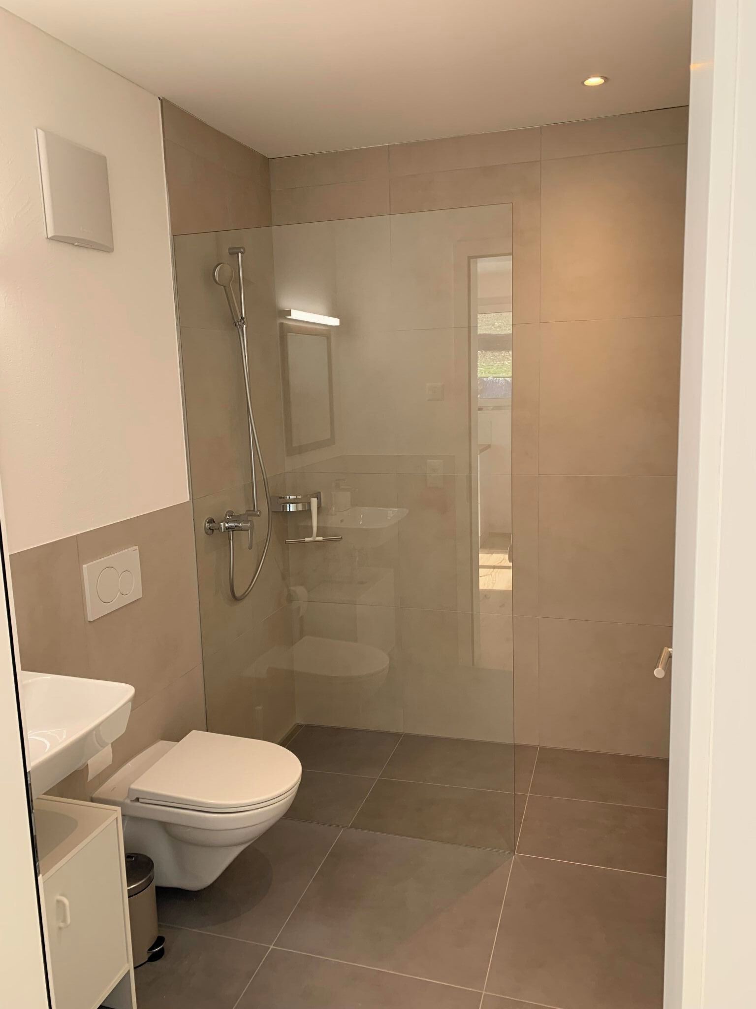A modern bathroom with a toilet, sink, and shower.