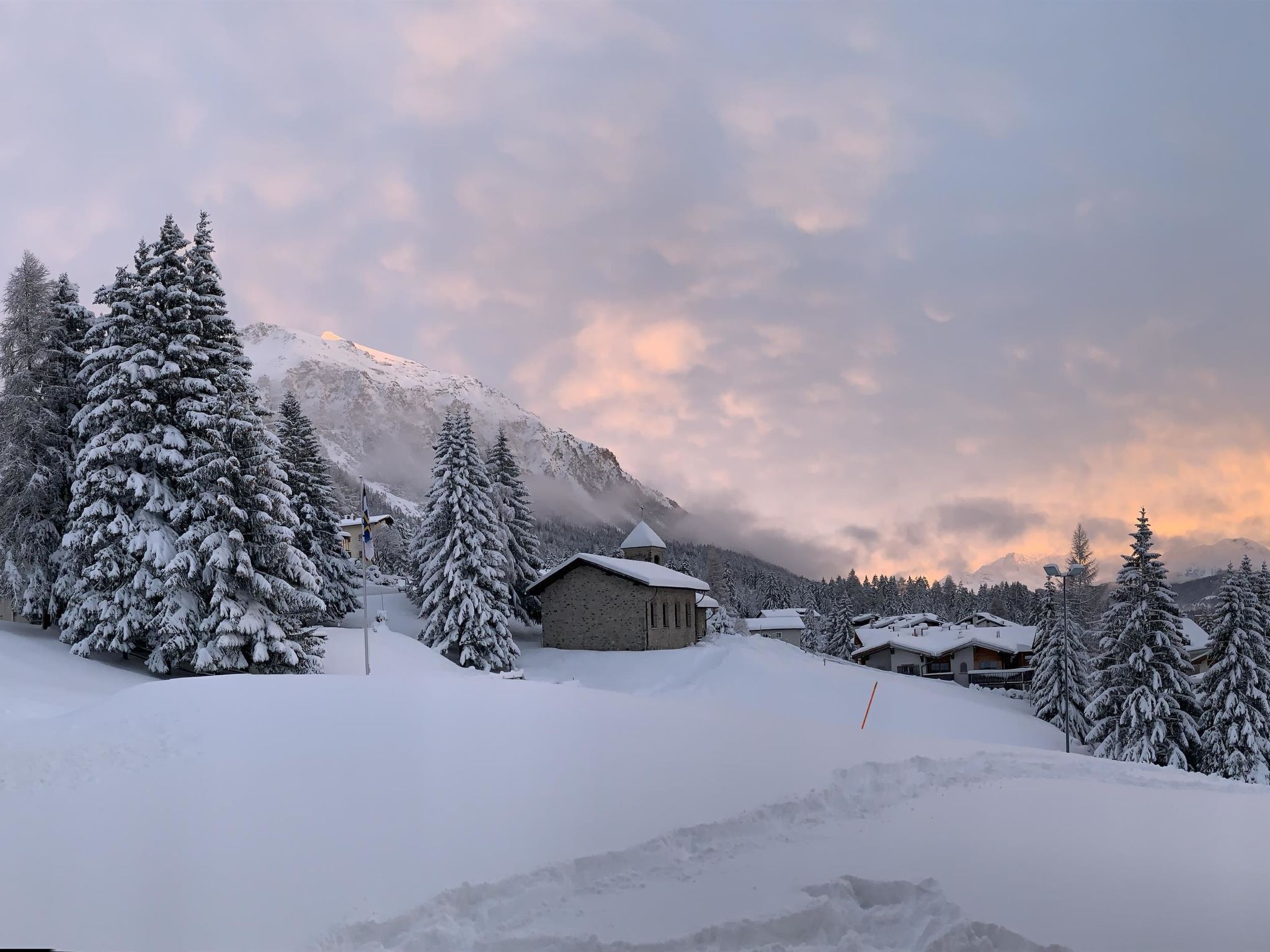 A snow-covered mountain landscape with a building surrounded by trees.