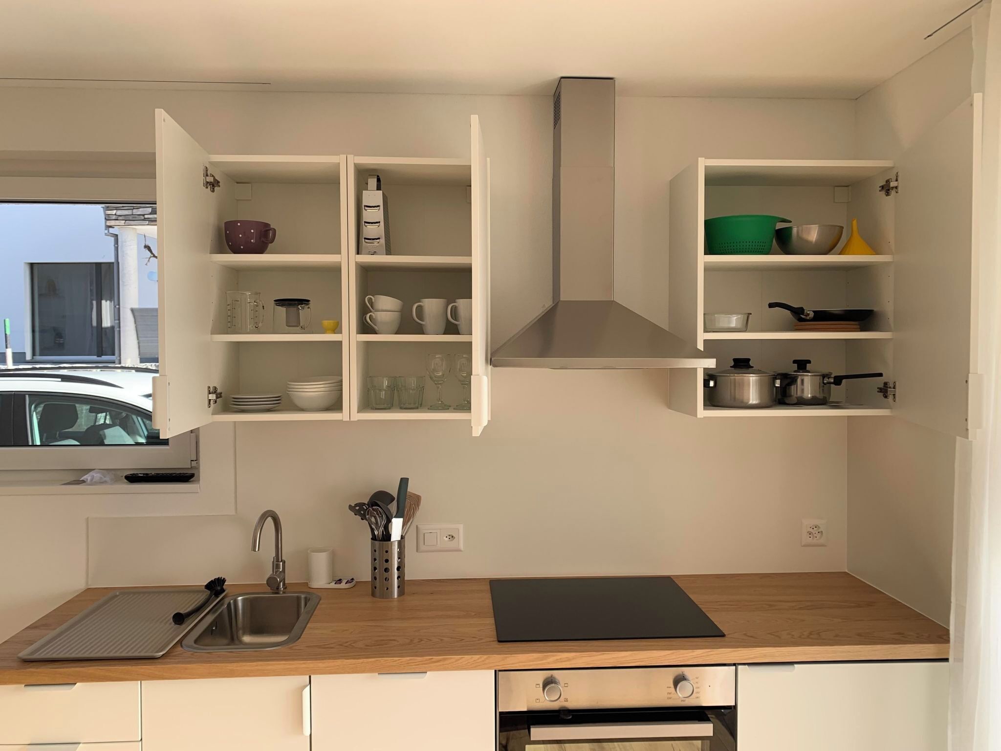 A modern kitchen with open cabinets, a sink, and a stove.