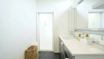 Un bany modern amb un lavabo blanc, dues aixetes, un mirall i un petit safata de brossa.