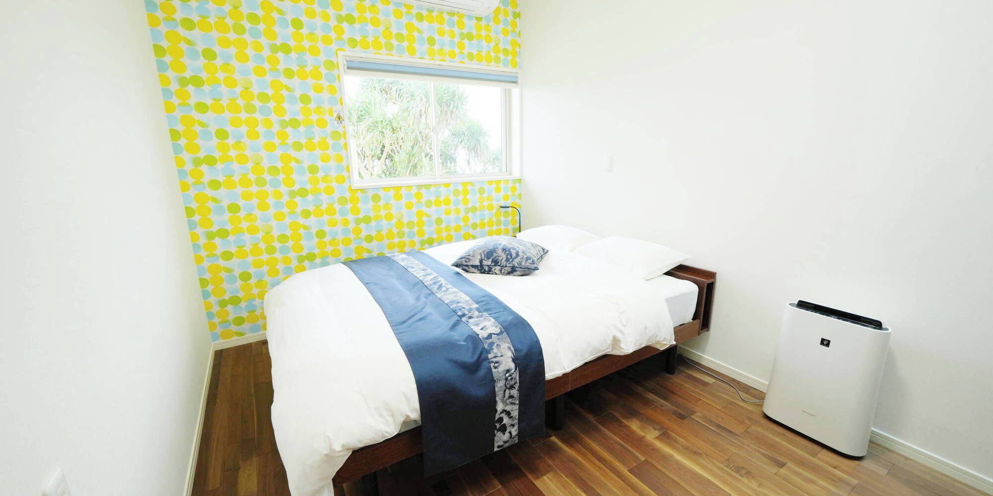 A bedroom with a bed, a window, and a white air conditioning unit.