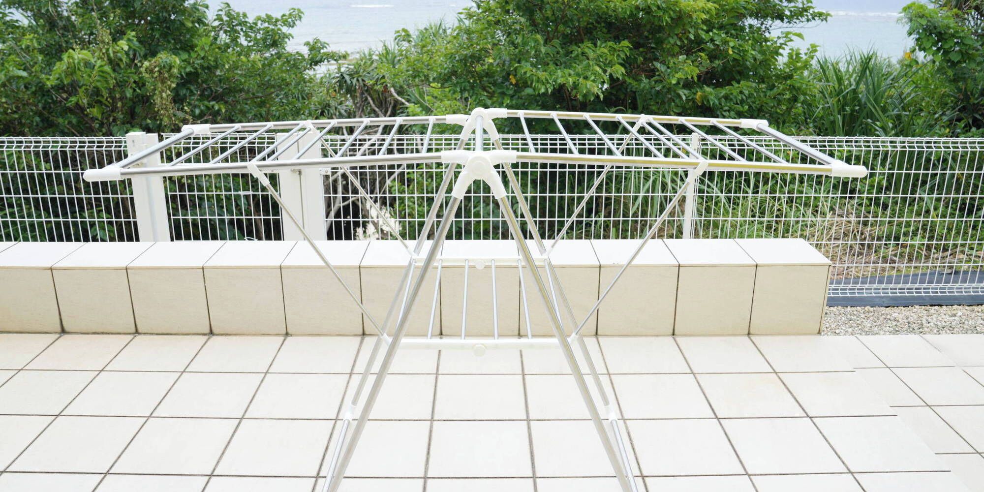 Een metalen constructie met een wit frame, mogelijk onderdeel van een gebouw of installatie, voor een achtergrond van groen en een betegelde vloer.