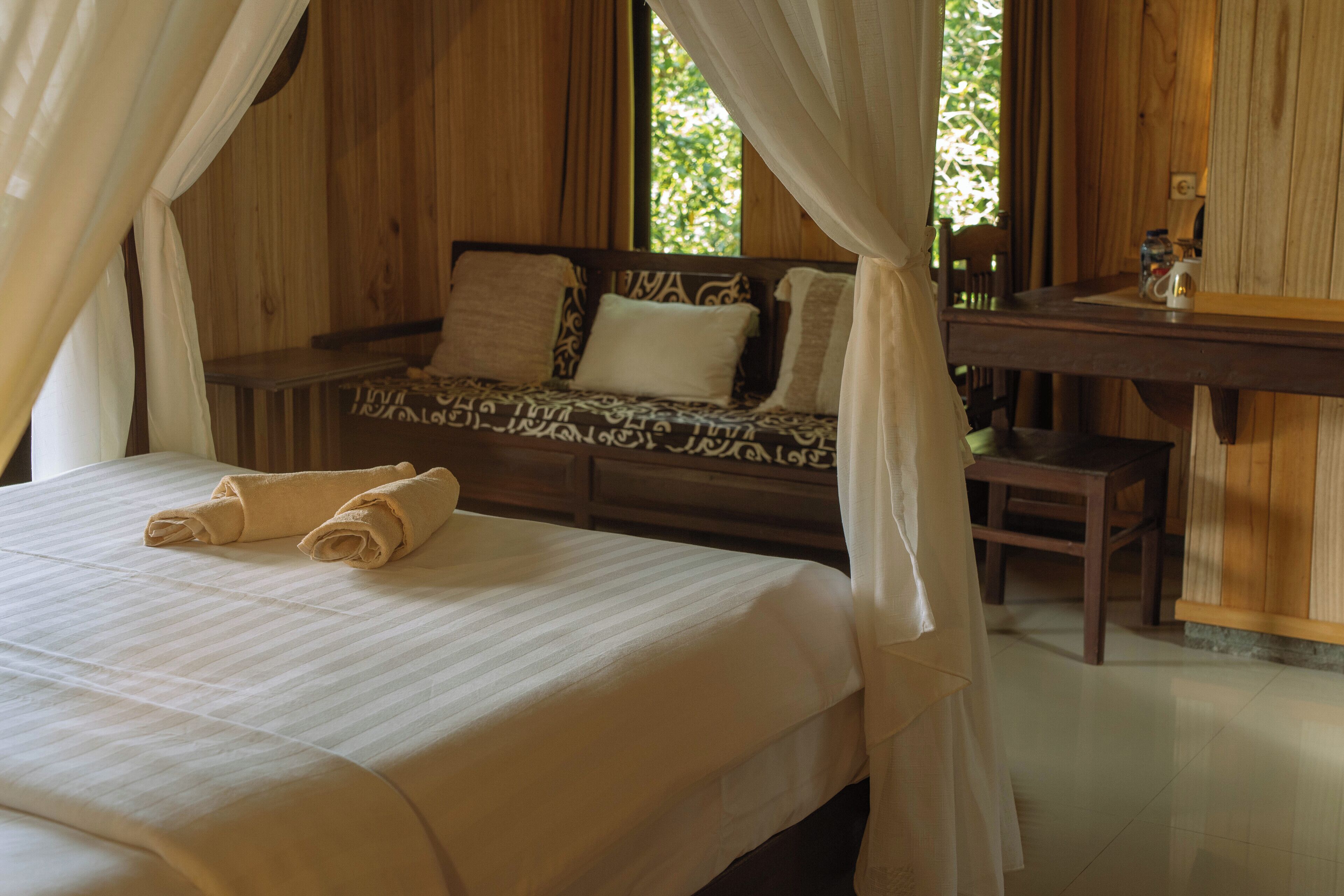 A wooden room with a bed, a bench, and a table.