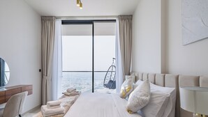Une chambre d’hôtel moderne dotée d’un grand lit, d’un bureau et offrant une vue sur la ville grâce à de grandes fenêtres du sol au plafond.