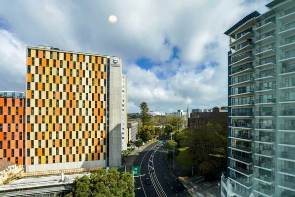 Un edificio moderno con fachada a cuadros, un letrero llamativo y vistas a una avenida con varios carriles y un carril exclusivo para autobuses.