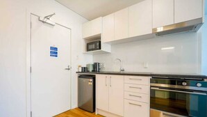 Een moderne keuken met witte kastjes, een roestvrijstalen koelkast, een magnetron, een spoelbak en een dubbele oven.