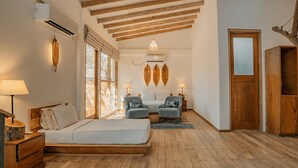 A bedroom with a wooden floor, a bed, two chairs, a nightstand, and a door. - O2 Villas Yala (Yala)