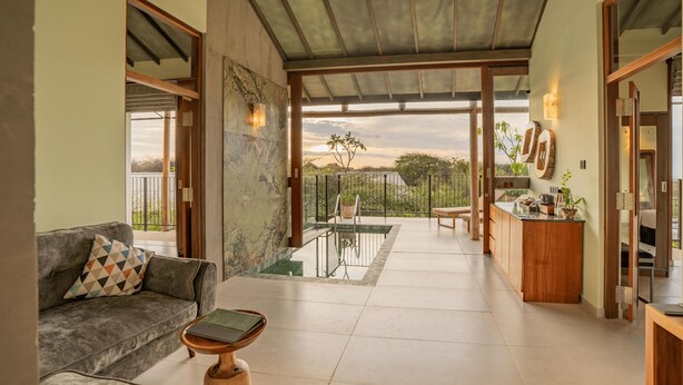 A spacious living area with a sofa, a coffee table, and a view of a balcony with a pool. - O2 Villas Yala (Yala)