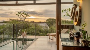 A modern outdoor pool area with a view of the sunset, a wooden bench, and a kitchen counter with plants. - O2 Villas Yala (Yala)