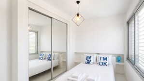 Ein Schlafzimmer mit einem Bett, einem Spiegel, einem Nachttisch und einem Fenster.