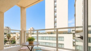 Ein Balkon mit Tisch, Stühlen, einer Topfpflanze und Blick auf Gebäude.