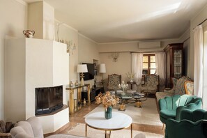 Un salon avec une cheminée, un téléviseur, une table basse et deux fauteuils verts.