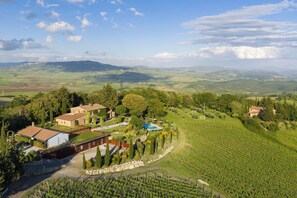 Una finca vinícola con varias construcciones, piscina y terrazas de viñedos.