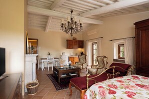 Una habitación tradicional con cama, una mesa de comedor, sillas, chimenea y un candelabro.