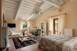 Ein Schlafzimmer mit einem Bett, einem Schreibtisch, einem Sessel, einem Fernseher und einem Bücherregal.